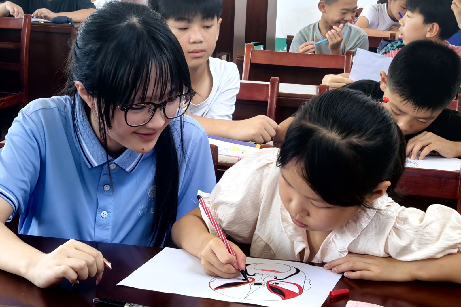 7月10日，孝感市孝昌县陡山乡城南中学暑假托管班上，志愿者在指导学生画京剧脸谱